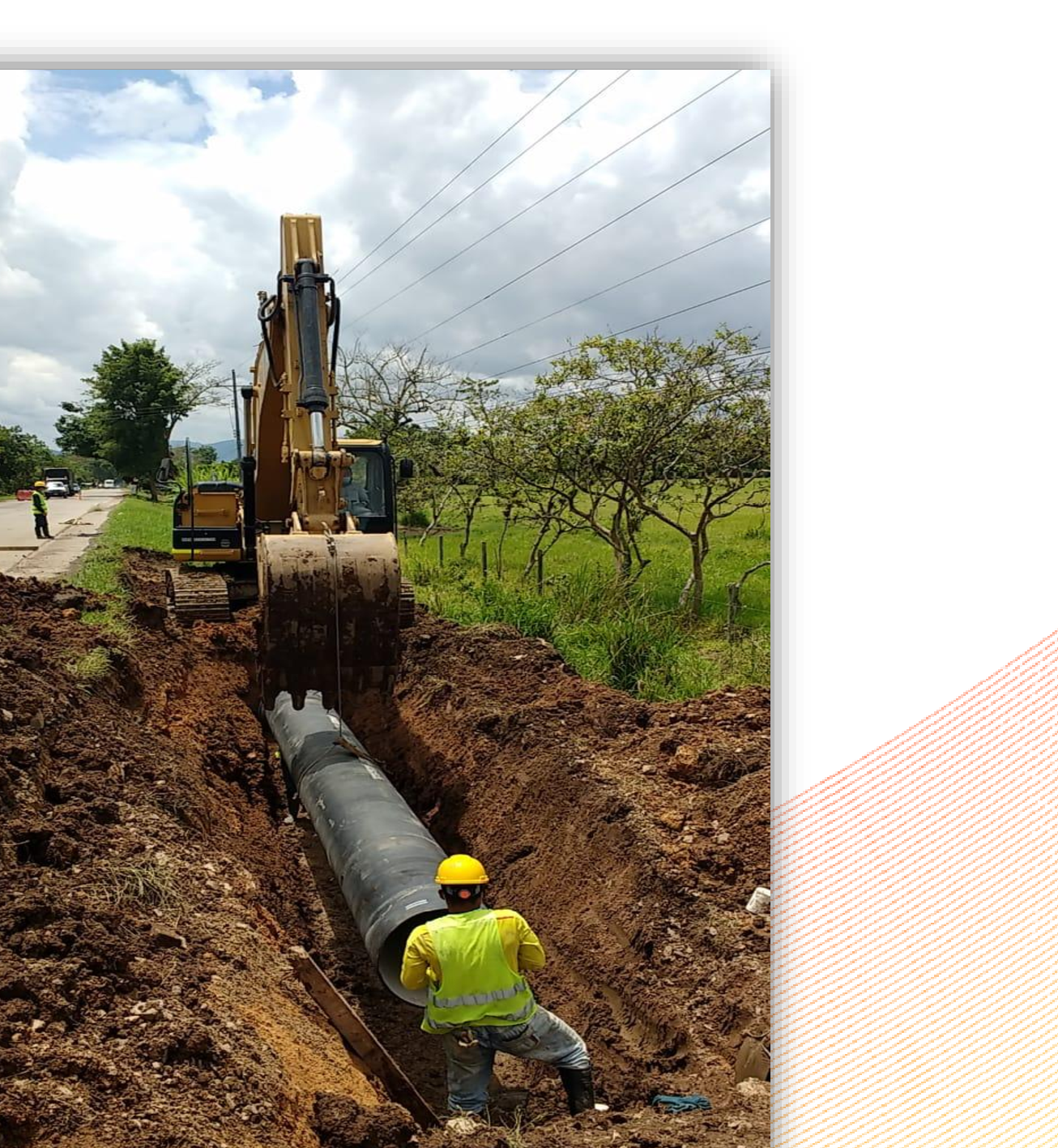 Excavadora y cuadrilla instalando tubería en una zanja de acueducto