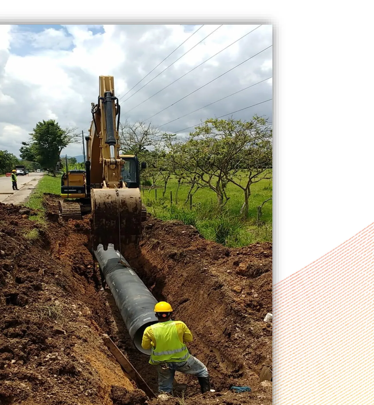 Excavadora y cuadrilla instalando tubería en una zanja de acueducto
