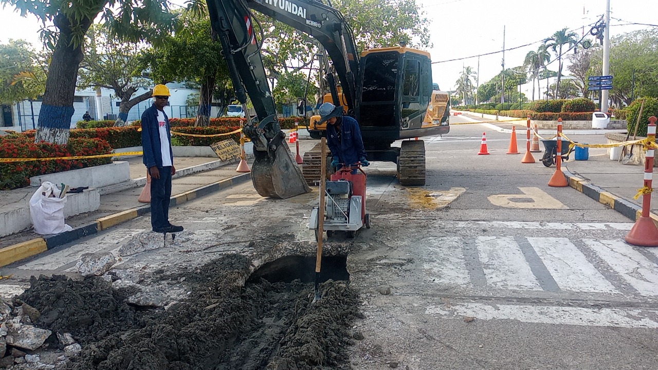 Excavadora y corte de pavimento junto a un cruce peatonal en una obra vial