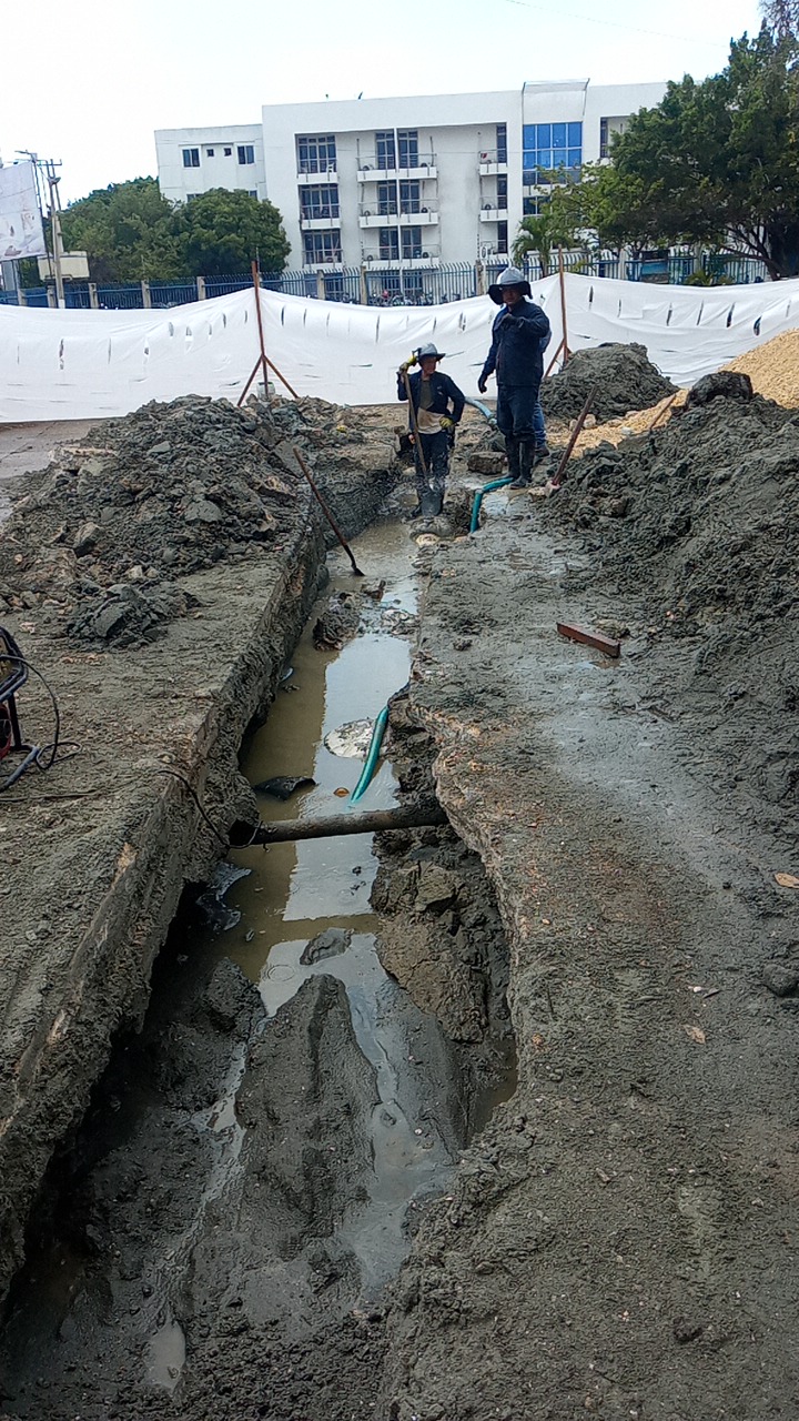 Cuadrilla instalando tubería en una zanja profunda de una obra de acueducto